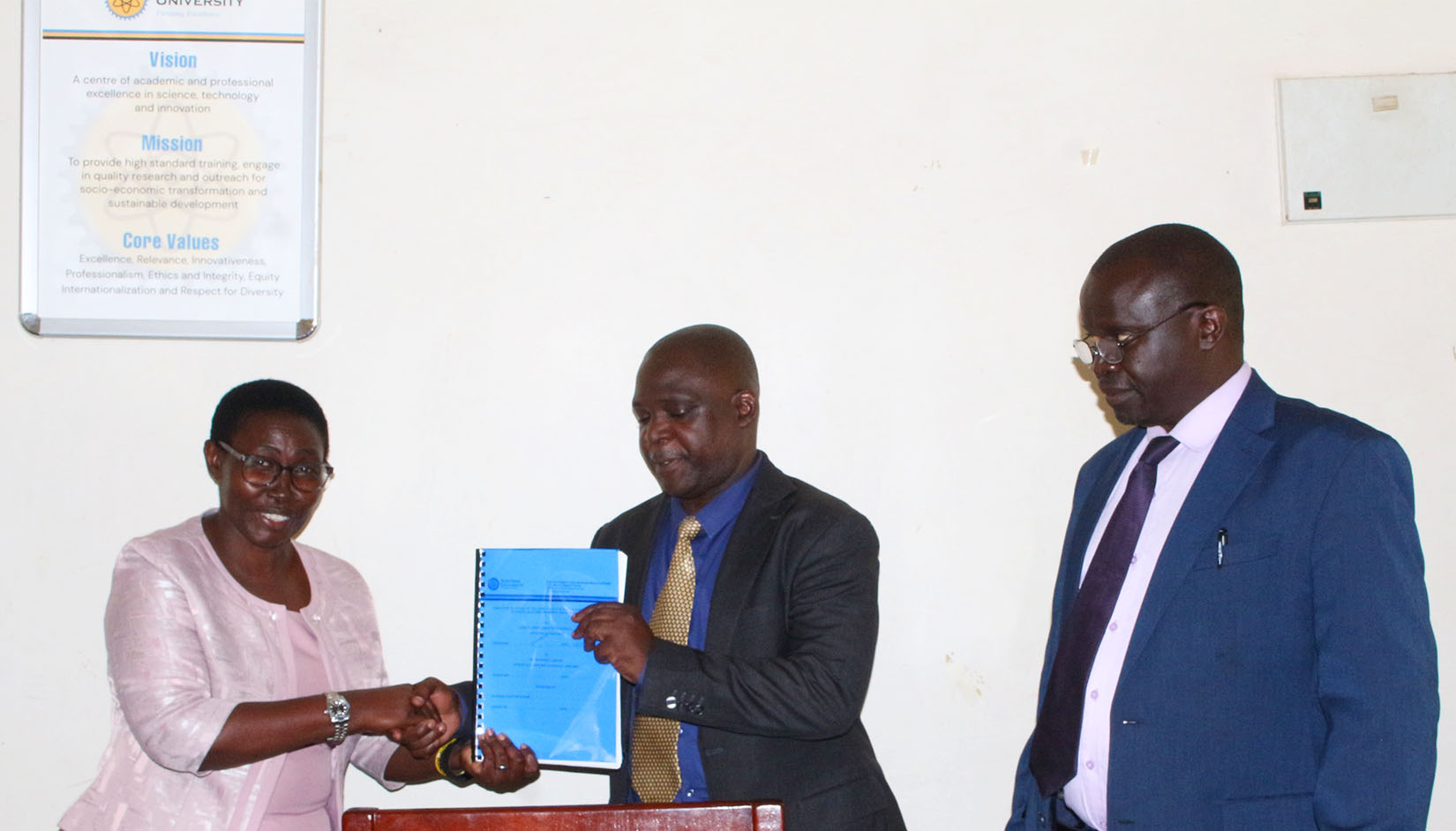 The Deputy Vice Chancellor for Academic Affairs hands over deanship instruments to the newly appointed Dean as the Vice Chancellor looks on